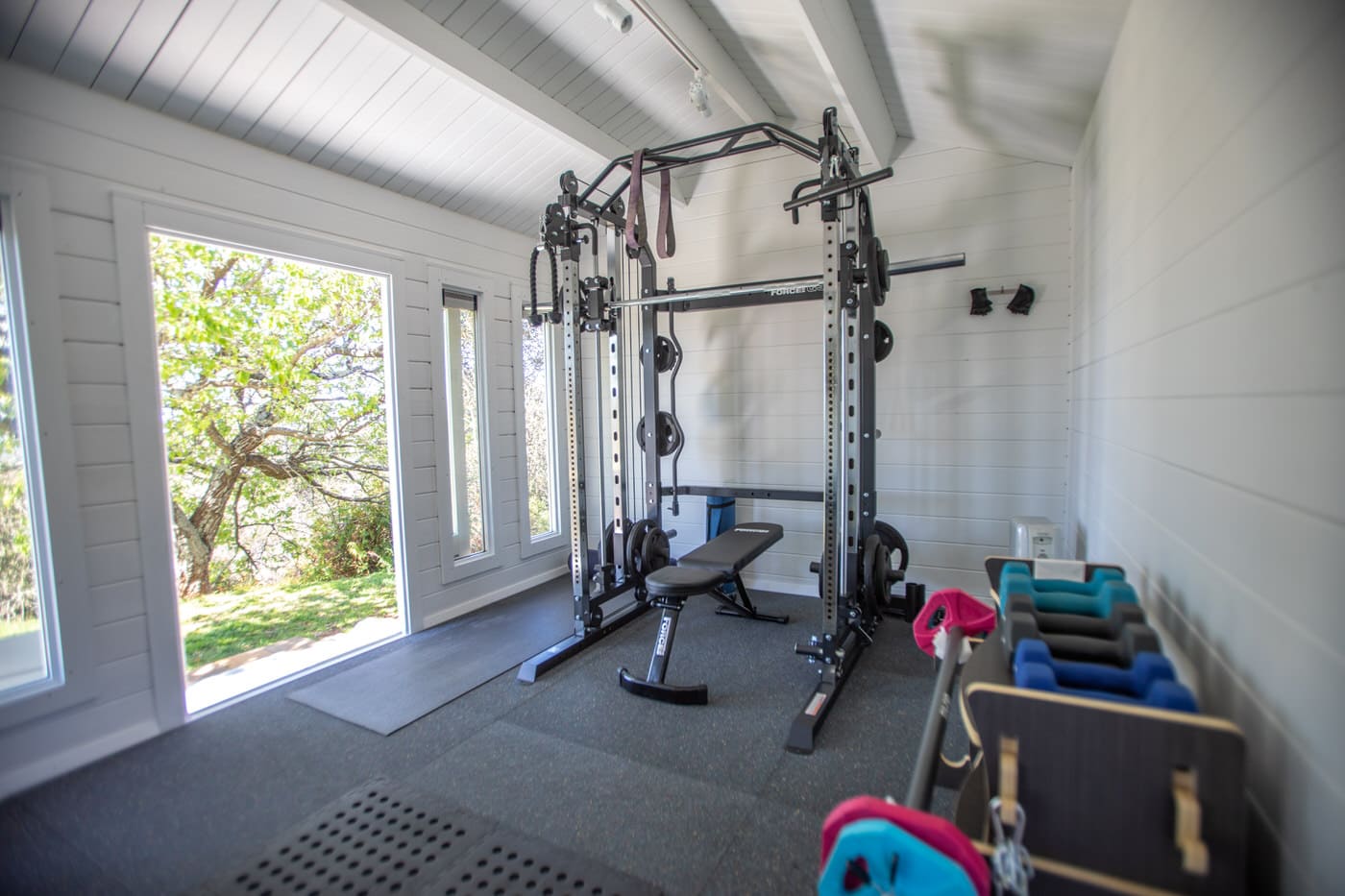 Lugarde Fitnessraum im Garten: Gummiboden, Spiegelwand, Hantelrack, gute Belüftung, Glas-Schiebetüren, modern.