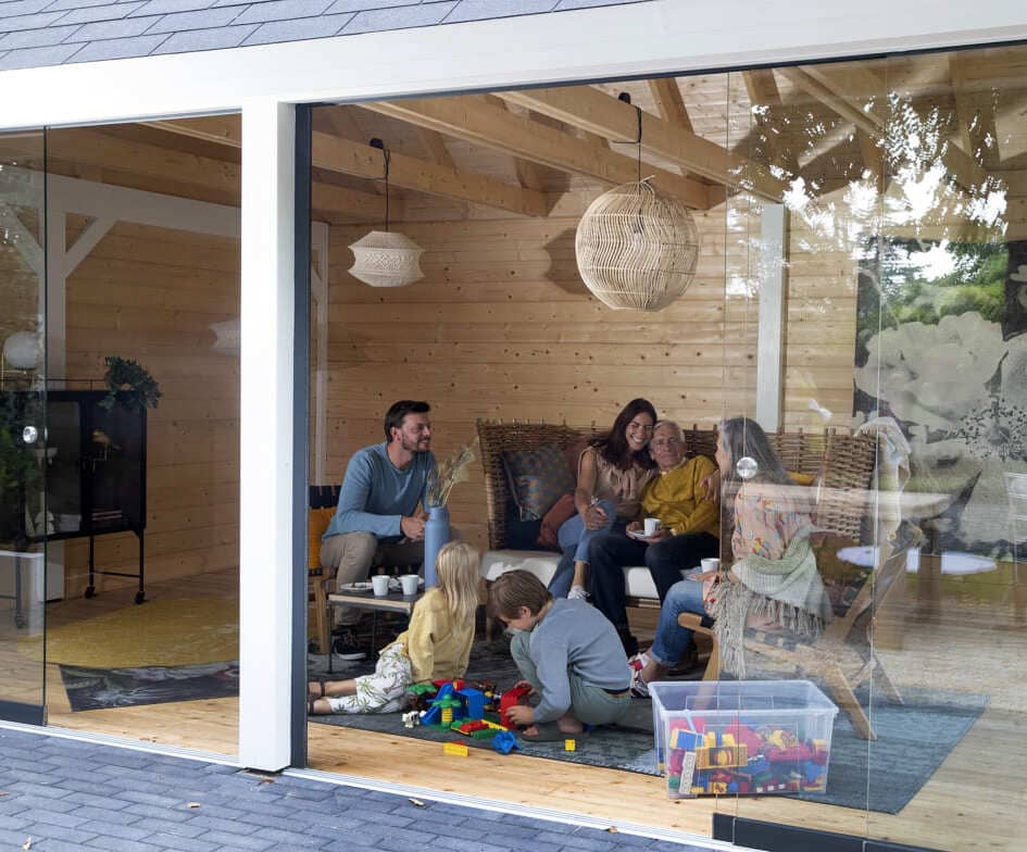 Freunde sitzen im gemütlichen Garten-Wohnzimmer von Lugarde, Kerzenlicht, Decken und Lachen – gemeinsame Zeit entspannt genießen.