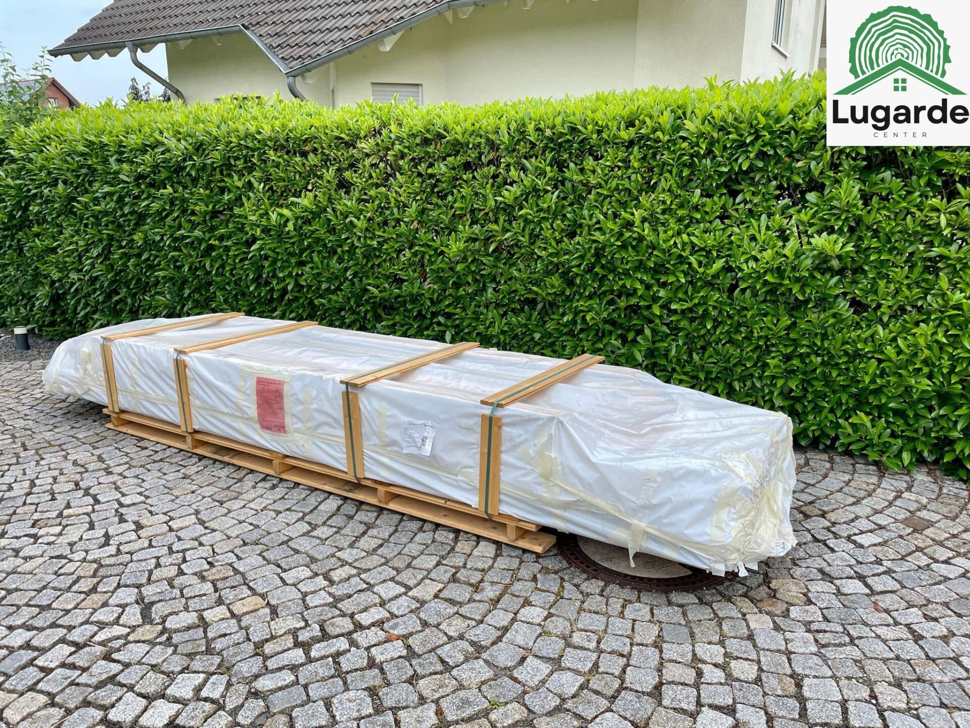 LKW mit Kran liefert Lugarde Bauteile an: enges Grundstück, präzises Einheben über Hecken, effizient und schonend, leise.