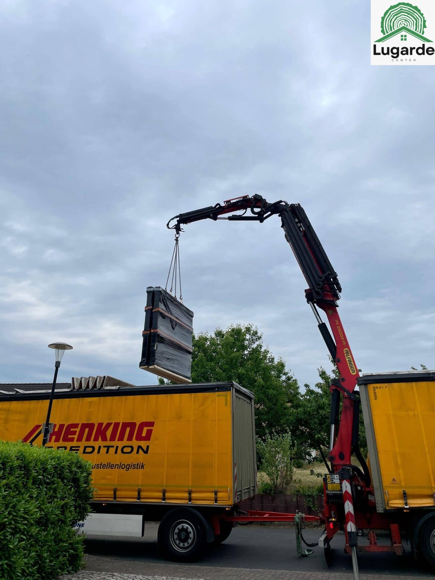 LKW mit Kran liefert Lugarde Bauteile an: enges Grundstück, präzises Einheben über Hecken, effizient und schonend, leise.