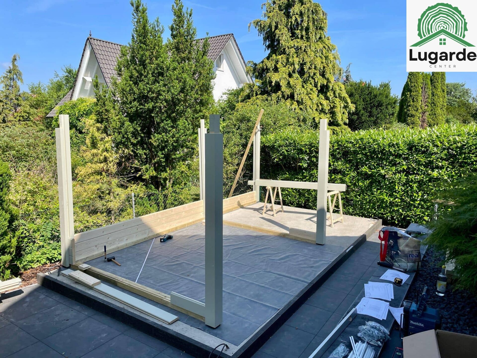 Flachdachhaus Kieselgrau, Detail: Dachüberstand und Pfosten; Sitzecke darunter, Glasfront bodentief, Grillzone seitlich.