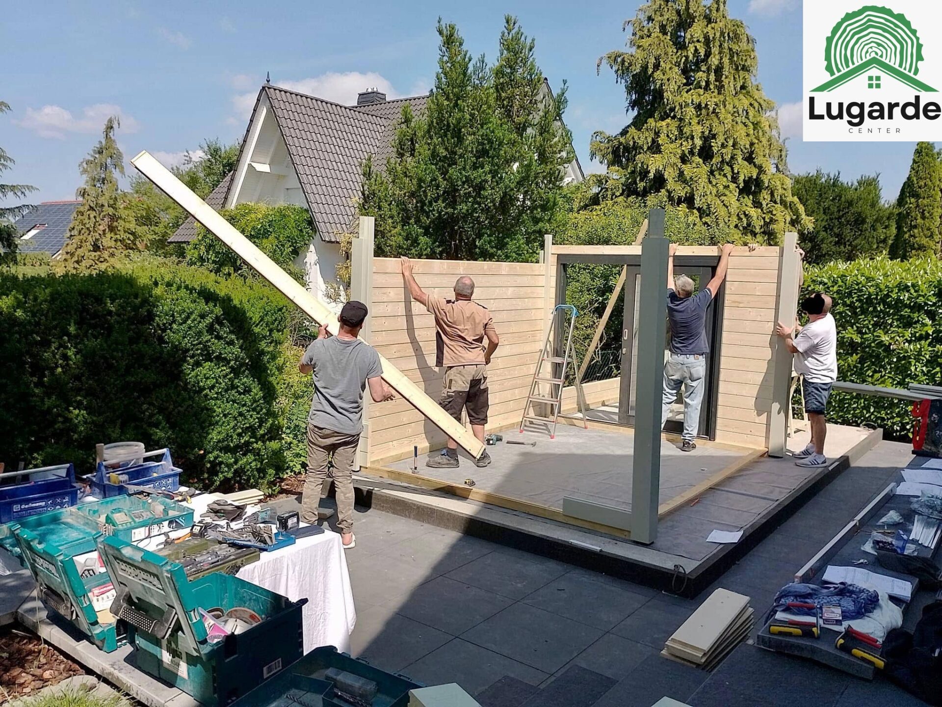 Innen-Außen-Blick: lichtdurchflutete Glasfront, Pro System in Kieselgrau; Dachüberstand deckt Sitzecke, Grillbereich daneben.
