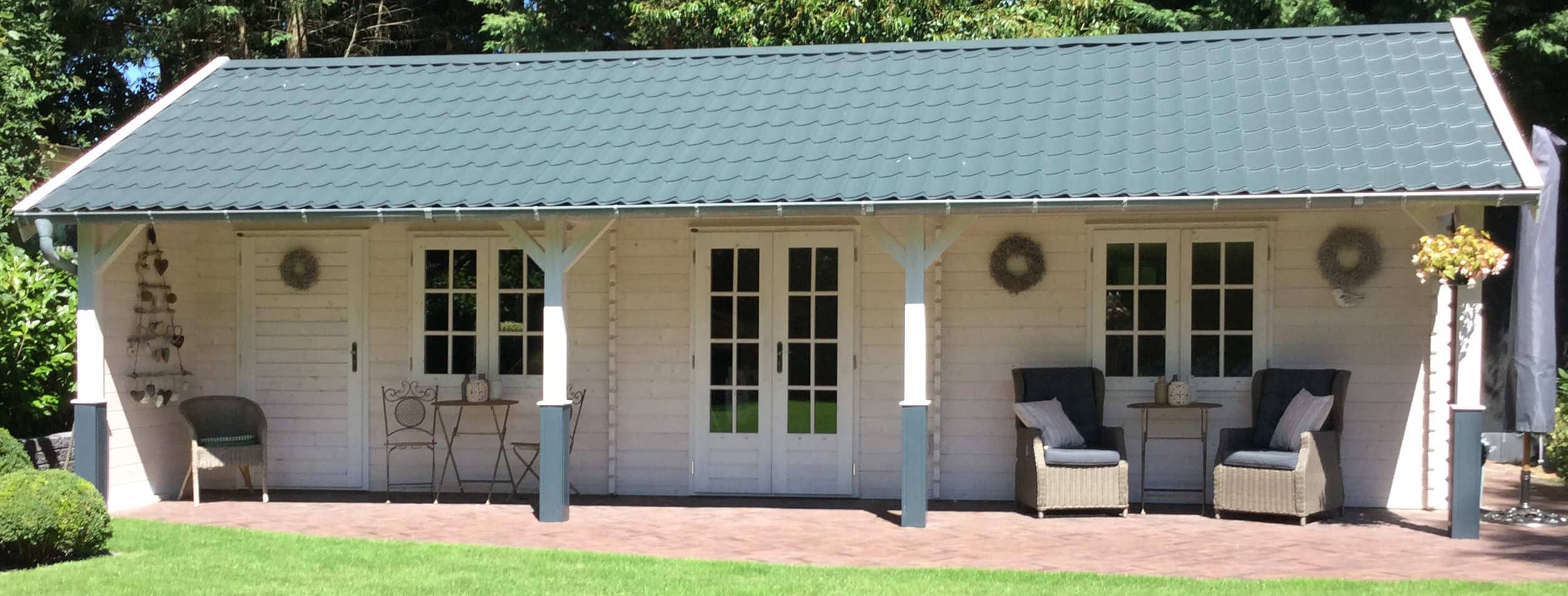 Kompaktes Tiny House als Gäste-Lodge mit breiter Sonnenterrasse und großen Fenstern vom Lugarde-Center im Grünen.